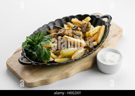 Bratkartoffeln mit Champignons auf Holzbrett Stockfoto