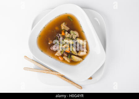 Suppe des Widders mit Brokkoli, Pilzen, grünen Bohnen und Kohl im weißen Teller Hintergrund Stockfoto
