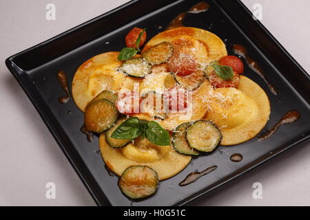 Ravioli gefüllt mit Kürbis und Amaretti Weißweinsauce auf schwarzem Teller Stockfoto