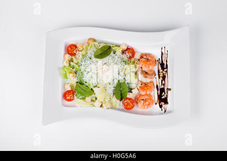 Caesar Salat mit Riesengarnelen, Tomaten und Kräuter auf weißen Teller Hintergrund Stockfoto