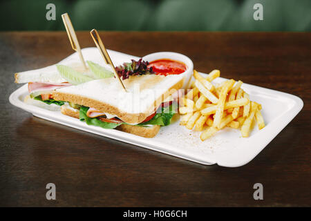 Schinken-Sandwich mit Pommes Frites und Chili-Sauce auf weißen Teller Stockfoto