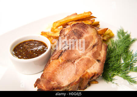 Gebackene Schinken Schweinerücken, gedünstet in Wein mit Knoblauch Crans serviert mit Bratkartoffeln und Senfsauce Stockfoto