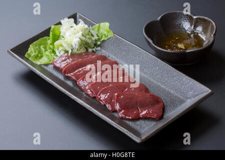 Rindfleisch gebratene Leber mit Sesamöl, Knoblauch-Soja-Sauce und Salat auf schwarzem Teller Stockfoto