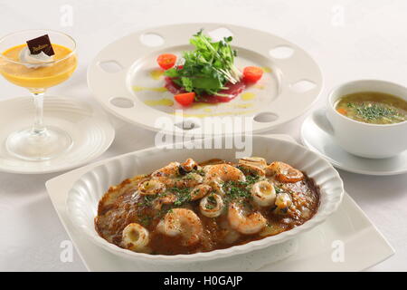 Tintenfisch und Oktopus Kuchen in großer Schüssel weiß mit Sprossen und Tomaten geschmort Stockfoto