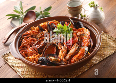 Gedämpfte Kimchi Meeresfrüchte mit Abalone, Miesmuschel, Tintenfisch, Krabben und Kräuter in große Schüssel auf koreanische Holztisch Stockfoto