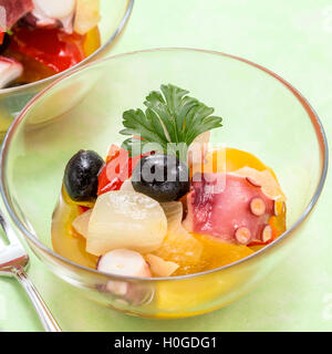 Sautierte Tintenfisch mit Oliven, Zwiebeln und Tomaten in Glasschale Stockfoto