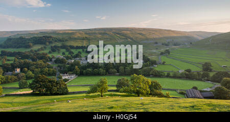 Sommer Abend Blick auf malerische Dales Dorf Arncliffe (Kirche & Häuser) eingebettet im Tal unter sonnenbeschienenen Hügeln - North Yorkshire, England, Großbritannien Stockfoto