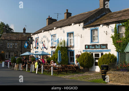 Die Menschen Essen und Trinken im Freien in der Sonne zu attraktiven, traditionellen englischen Pub - Der Blue Bell Inn, Kettlewell Dorf, Yorkshire Dales, England, UK. Stockfoto