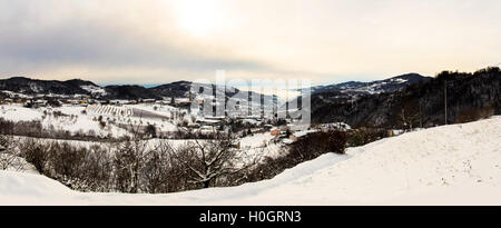 Panorama der schneebedeckten Wiese umgeben von Bergen. Stockfoto