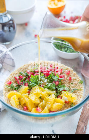 Couscous-Salat mit Orangen-Vinaigrette in Glasschüssel in der Küche Stockfoto