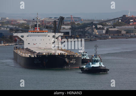 Voll beladen, Bulk Carrier Amakusa Insel verlassen den Hafen von Newcastle von drei Schlepper Newcastle Australien unterstützt Stockfoto
