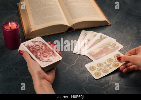 Hexe mit esoterischen Objekt für Heilung und Wahrsagerei; Kerze, Tarots und Buch, Vintage-Stil. Stockfoto