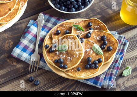 Pfannkuchen mit Heidelbeeren, Minze und Honig zum Frühstück - hausgemachte gesunde vegetarische Speisen auf Teller Stockfoto