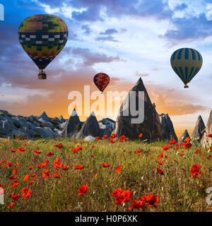 Heißluftballons fliegt über ein Feld von Mohn und Felslandschaft in Kappadokien, Türkei Stockfoto