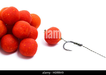 Nahaufnahme der Angeln Köder für Karpfen. Zubehör für Karpfen. Blick auf Angelhaken und mehrere rote Boilies isoliert Stockfoto