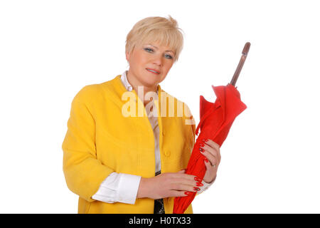 Frau mittleren Alters in einer gelben Jacke mit einem roten Regenschirm auf weißem Hintergrund Stockfoto