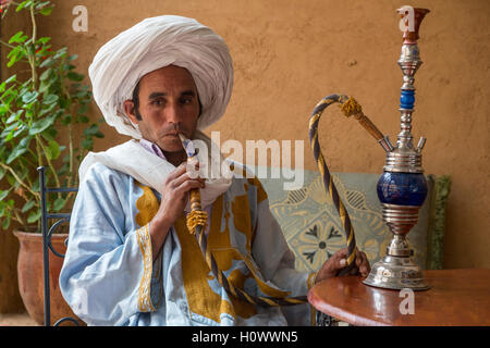 In der Nähe von Ait Oudinar, Dades Schlucht, Marokko.  Berber Jüngling Rauchen einer Wasserpfeife (Shisha). Stockfoto