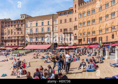 Menschen sitzen und gehen auf der Piazza del Campo in Siena, Italien Stockfoto