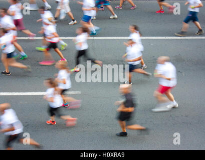 Menschen in weißen T-shirts laufen Halbmarathon auf Stadtstraßen in Aufmerksamkeits Motion blur Stockfoto