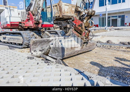 Kleine Bagger entfernt gebrochen Asphalt und Kies auf Baustelle. Stockfoto