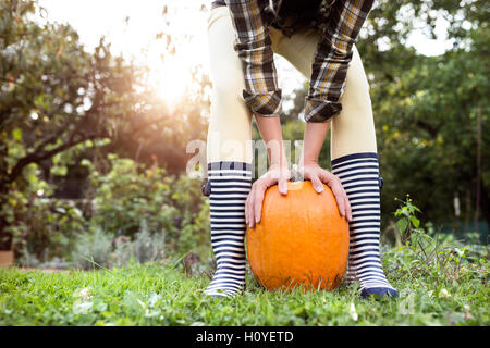 Nicht erkennbare Frauen in gestreiften Gummistiefel halten orange Pumpe Stockfoto