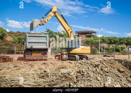 Ein Bagger Bagger füllt einen LKW-LKW mit Stein während einer Ausgrabung auf der Baustelle. Stockfoto