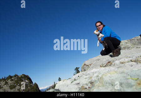 Chinesischen kanadischen Mann, Wandern mit Hund Jack Russell auf British Columbias Mount Seymour mit schneebedeckten Berge und blauer Himmel Stockfoto