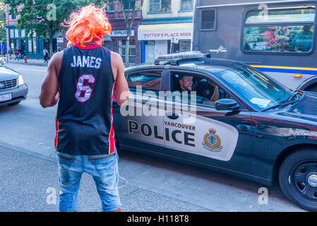 Mann mit orange Perücke spricht mit Polizisten im Streifenwagen, DTES Hastings Street Vancouver, British Columbia, Kanada, Stockfoto