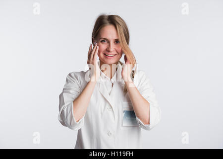 Junge Ärztin oder Krankenschwester ist mit den Händen auf den Mund schockiert. Stockfoto