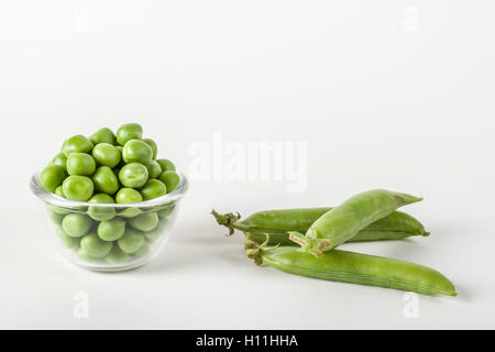 Frisch geschälte Erbsen in eine Glasschale und ganze Erbsen auf weiß Stockfoto