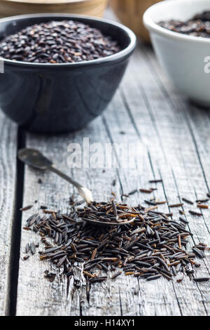 Wildreis in Löffel auf alten Holztisch. Stockfoto