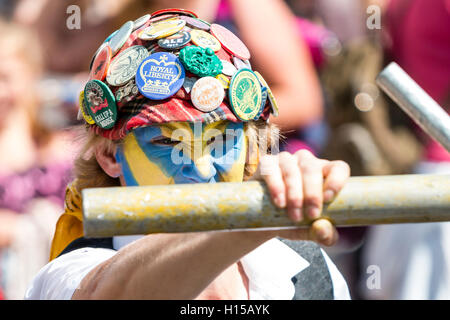 In der Nähe von Royal Liberty Morris Tänzerin, junger Mann, mit gelb und blau lackiert, trägt rote Kappe in Abzeichen abgedeckt, Fechten mit Metall Pol. Stockfoto