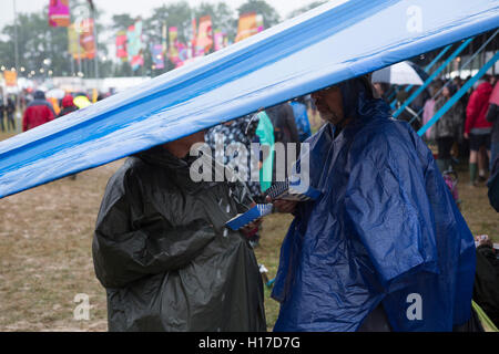 Festivalbesucher nehmen Sie die Abdeckung vor dem Regen beim Womad Festival 2015. Stockfoto