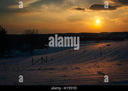 Sonnenuntergang über schneebedeckten Hügeln und Feldern im Carroll County, Maryland. Stockfoto