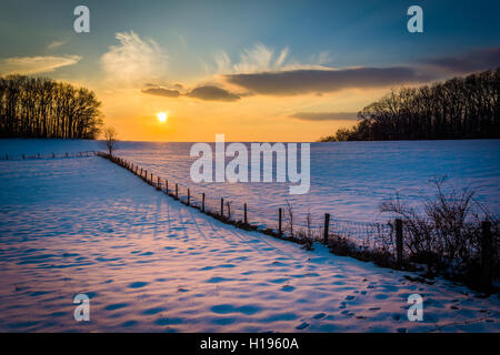 Winter-Sonnenuntergang über einen Zaun und Schnee überdachten Hof-Feld im ländlichen Carroll County, Maryland. Stockfoto