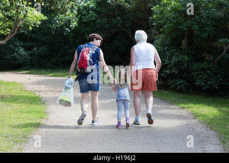 Drei Generationen von Frauen; Kind, Mutter und Großmutter, die in einem Park spazieren, von hinten gesehen, Großbritannien - Mehrgenerationenfamilie. Stockfoto