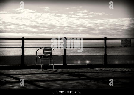 "Nach der Tea'. Eine leere Tasse sitzt auf einem leeren Stuhl, Blick auf das Meer von Worthing Pier.  23.09.2016 in Worthing Beach, Worthing. Bild von Julie Edwards. Stockfoto