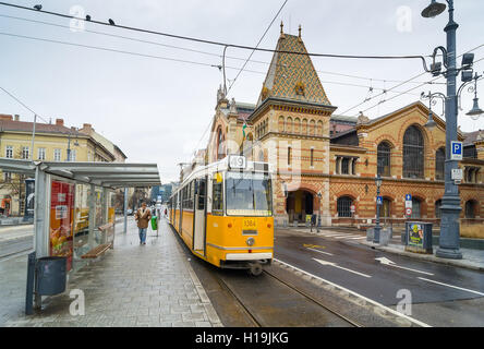 BUDAPEST, Ungarn - 21. Februar 2016: Gelbe Straßenbahn und große Markthalle in Budapest, Ungarn. Stockfoto