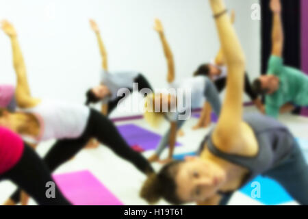 Gruppe von Menschen praktizieren Yoga im Health Club verwischt. Yoga, Sport, Fitness, Lifestyle und Menschen-Konzept. Stockfoto