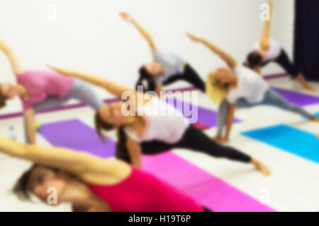 Gruppe von Menschen praktizieren Yoga im Health Club verwischt. Yoga, Sport, Fitness, Lifestyle und Menschen-Konzept. Stockfoto
