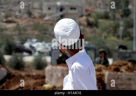 Nablus, West Bank, Palästina. 23. Sep, 2016. Palästinenser führen Freitagsgebet, wie israelische Soldaten auf, neben der Beta Junction Ost West Bank Stadt Nablus, aussehen, aus Protest gegen die Schließung des Eingangs des Dorfes Beta von der israelischen Armee. Bildnachweis: Mohammed Turabi/ImagesLive/ZUMA Draht/Alamy Live-Nachrichten Stockfoto