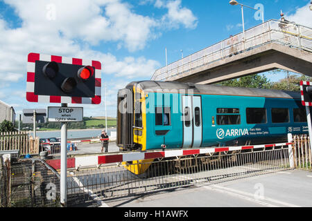 Arriva Zug vorbei Schranke eines Bahnübergangs am Ferryside Dorf Bahnhof, Carmarthenshire, West Wales,U.K.,GB,Europe. Stockfoto