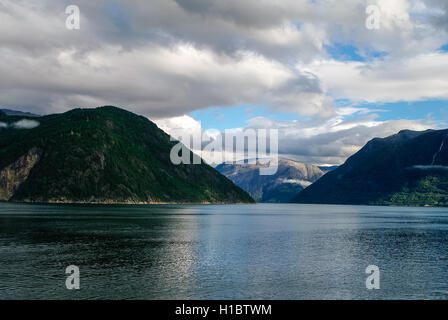 Bewölkter Himmel über Ufer des Fjords. Berge mit grünen Wäldern, Eidfjord, Norwegen Stockfoto