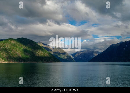 Bewölkter Himmel über Ufer des Fjords. Berge mit grünen Wäldern, Eidfjord, Norwegen Stockfoto