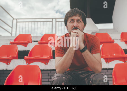 Enttäuschter Mann im Sportstadion das Spiel ungläubig beobachten, während seine Mannschaft das Spiel verliert Stockfoto