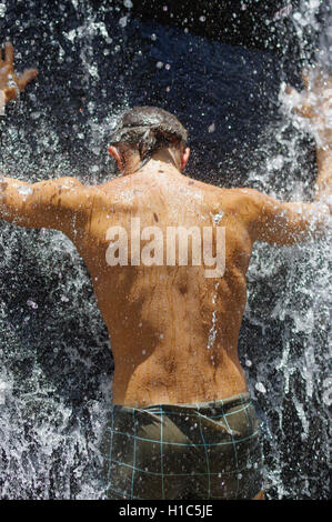 Mann, der eine entspannende Dusche unter einem Wasserfall. außerhalb Stockfoto