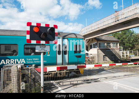 Arriva Zug vorbei Schranke eines Bahnübergangs am Ferryside Dorf Bahnhof, Carmarthenshire, West Wales,U.K.,GB,Europe. Stockfoto