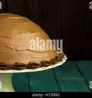 Schokolade Kaffee halbe Kugel Haselnusskuchen mit dekorativen Paspeln auf weißen Kuchen stehen dunkel und türkisfarbenen Hintergrund Stockfoto