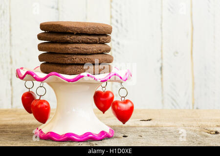 Mexikanische heiße Schokolade in Herzform Shortbread mit Cayenne-Pfeffer und Zimt auf Antike Stand mit roten Herz Anhänger Stockfoto