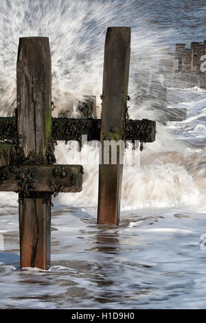 Meerwasser bricht durch Buhnen am Strand in Zeitlupe Stockfoto